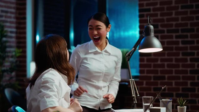 Cheerful coworkers read email on laptop received from customer, excited after managing to secure lucrative deal for company. Colleagues celebrate finalizing agreement with business partners, camera B