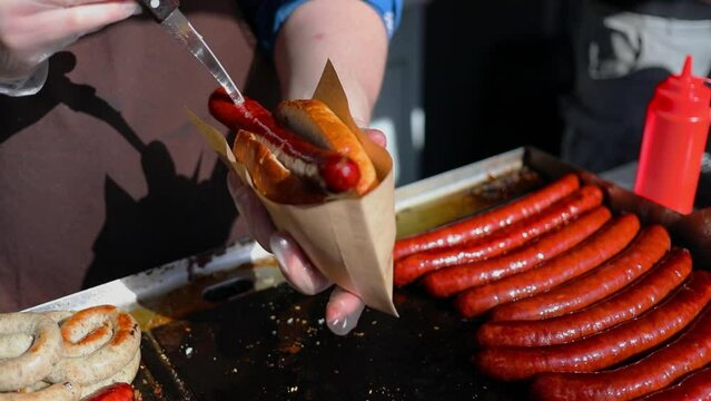 Man prepares hotdog and pierces sausage by knife. Slow motion