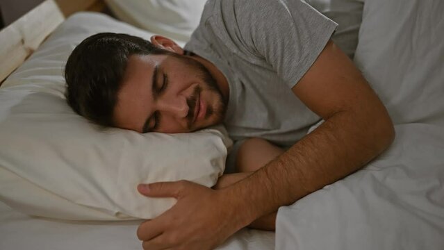 A young hispanic man with a beard enjoys a peaceful sleep in a cozy bedroom setting, exhibiting a sense of relaxation and comfort.