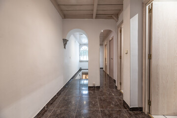 Corridor of residential house with white oak wooden doors, glossy dark stoneware floors