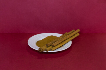 Cinnamon sticks next to ground cinnamon on saucer in beautiful details