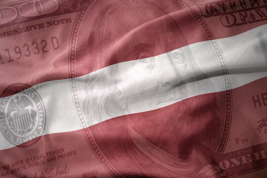 waving colorful flag of latvia on a american dollar money background. finance concept.