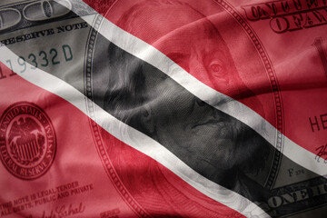 waving colorful flag of trinidad and tobago on a american dollar money background. finance concept.