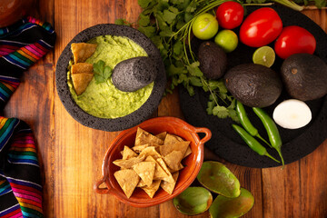 Guacamole. Avocado dip with tortilla chips also called Nachos served in a bowl made with volcanic stone mortar and pestle known as molcajete. Mexican easy homemade sauce recipe very popular.