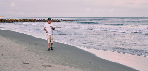 Older man walking on the beach at the seashore in Cartagena de Indias, Colombia.
