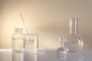 Laboratory analysis. Different glassware on table against beige background