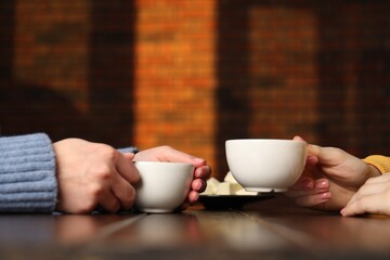 Women having coffee break at wooden table in cafe, closeup