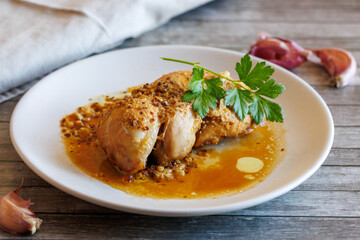 Glazed Chicken breast in a honey Sweet and Sour marinade with garlic and orange juice on white plate on wooden table