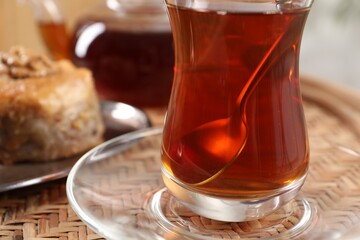 Traditional Turkish tea in glass on wicker table, closeup