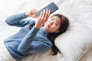 ベッドで寝る前にスマホを使う若い女性