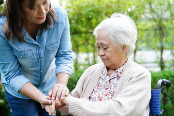 Caregiver help Asian elderly woman disability patient sitting on wheelchair in park, medical...