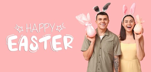 Happy young couple with bunny ears and gifts on pink background. Easter greeting banner