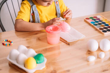 Little girl paints artificial eggs for Easter.