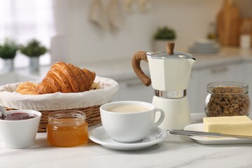 Breakfast served in kitchen. Fresh coffee, granola, croissants, jam, butter and honey on white table