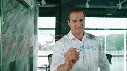 Smart businessman thinking about start up project in front of glass board. Smiling male project...