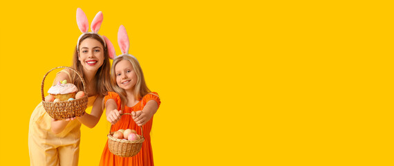 Happy mother and her little daughter with Easter baskets and bunny ears on yellow background with space for text