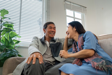 Older couples sit and chat and head over each other relaxed and happy on sofa at home on weekday in...