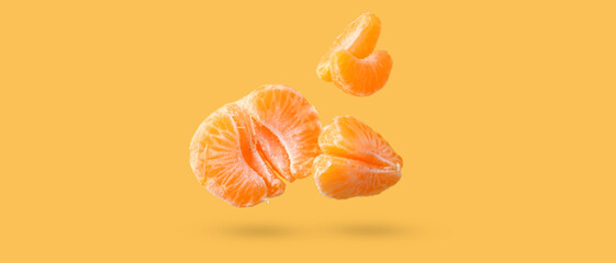 Flying sweet peeled mandarins on orange background