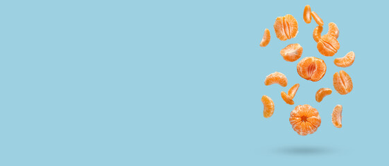 Flying sweet peeled mandarins on blue background with space for text