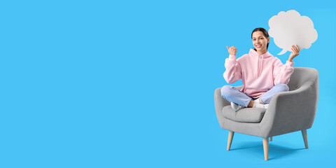 Young woman with blank speech bubble sitting in armchair on light blue background with space for text