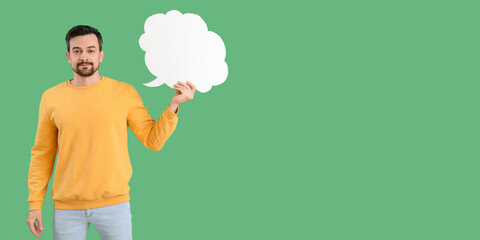 Handsome man holding blank speech bubble on green background with space for text