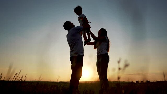 family standing on the field. happy childhood concept for little child. big happy family stands on field, parents raised the child in their arms, sunset on the background, silhouettes lifestyle