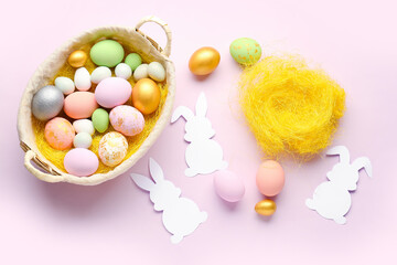 Paper rabbits and basket with Easter eggs on pink background