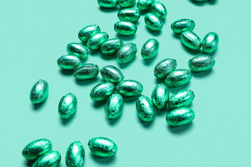 Chocolate Easter eggs in foil on color background