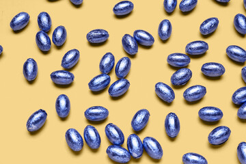 Chocolate Easter eggs in foil on color background
