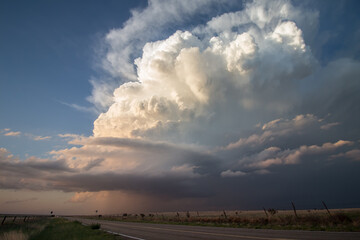 A cumulonimbus cloud, also known as a thunderstorm billows upward in the sky over a desolate landscape.