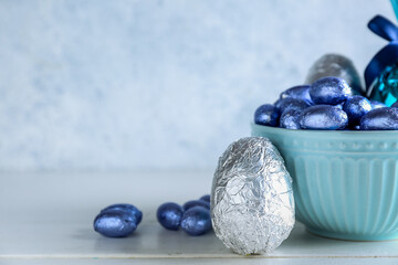 Bowl of chocolate Easter eggs on light wooden table