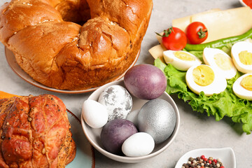 Bowl with beautiful painted eggs and tasty dishes for Easter dinner on table, closeup