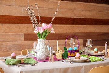 Beautiful Easter table setting with flowers and eggs in dining room