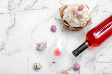 Composition with Easter cake, eggs, glass and bottle of wine on light background