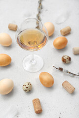 Fototapeta na wymiar Composition with glass of wine, Easter eggs, willow branches and corks on light background