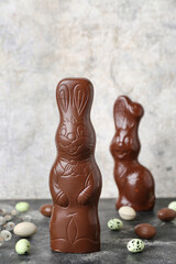 Chocolate Easter bunny with eggs and willow branches on table against grunge background