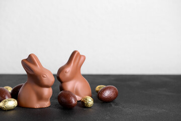 Chocolate Easter bunnies and eggs on black table against white background