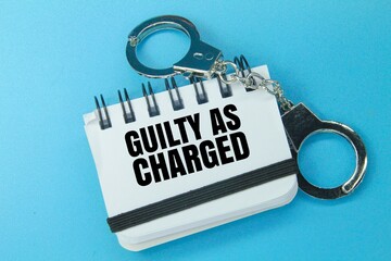 iron handcuffs and a book with the word guilty as charged. the concept of guilt as accused