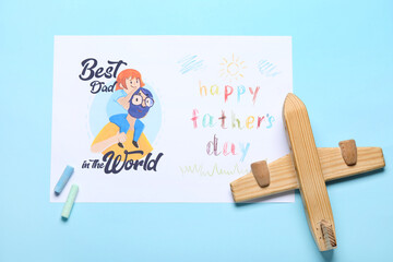 Card for Father's Day with chalks and wooden airplane on blue background