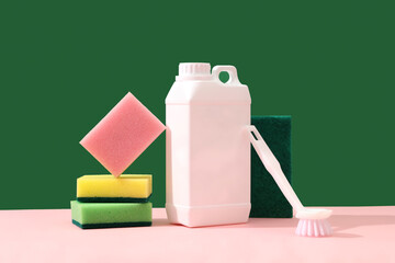 Colorful cleaning products on a green background and pink plain with colorful sponges, brush and...