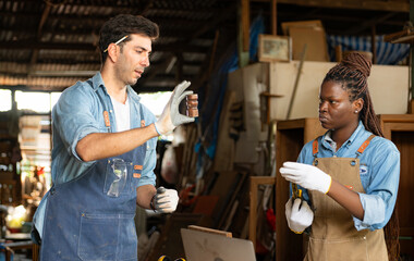 Carpenter and his assistant working together in a carpentry workshop