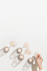 Rose wineglass in woman hand, Minimal style flat lay. Holiday aesthetic still life photo, top view wine glasses at sunlight, sun shadow, monochrome beige peach pink pastel color, copyspace