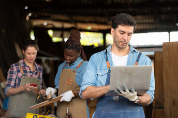Portrait of carpenter male worker standing with laptop in workshop