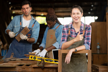 Portrait of carpenter female worker standing in front of colleague in workshop, Eyesight is...