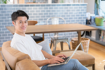 Handsome middle-aged Asian (Japanese) man using a computer in a cafe or at home.Spring/Summer Image