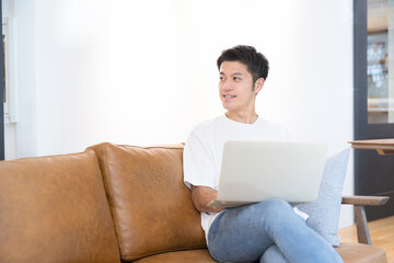 Handsome middle-aged Asian (Japanese) man using a computer in a cafe or at home. Spring/Summer Image