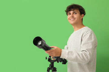 Young man with telescope on green background