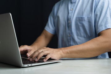 A man uses a smartphone or tablet in a dark room. Holding hands. Black background. Home office. For work. For social media or searching for information