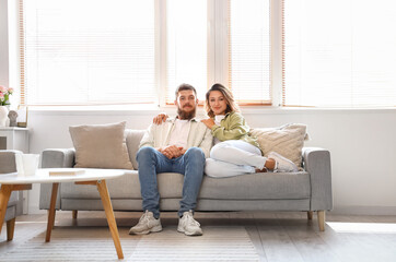 Happy couple in love sitting on sofa at home