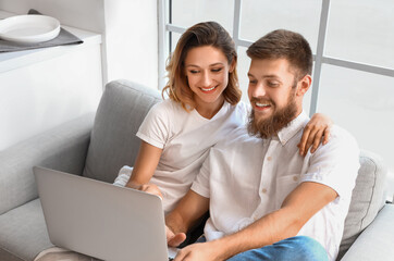 Fototapeta premium Happy couple in love using laptop in kitchen